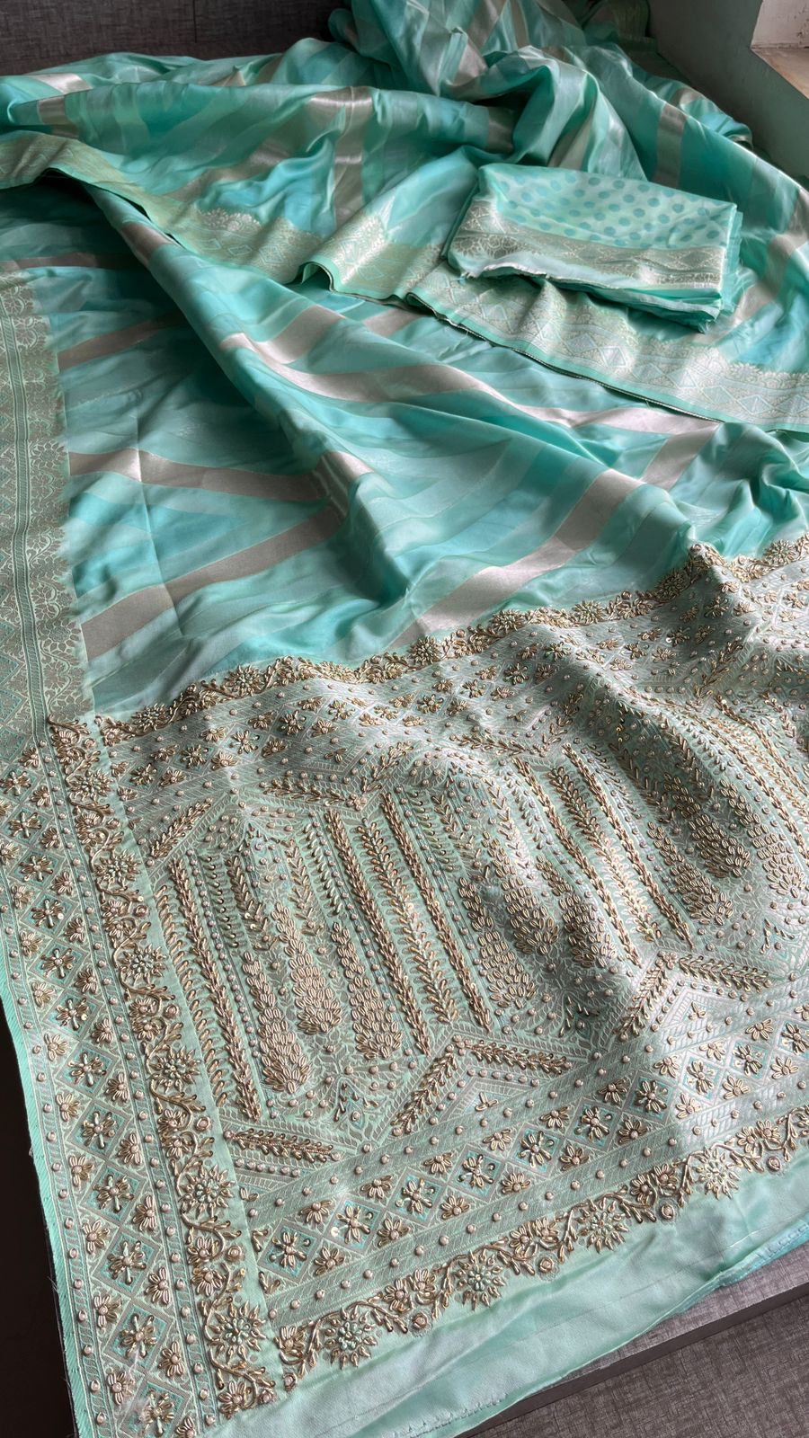 Turquoise fabric with intricate gold embroidery on a flat surface